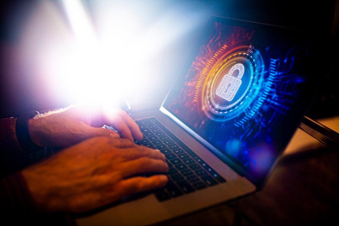 A person's hands shown at work on an open laptop depicting an image of a white lock.