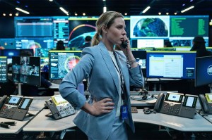A female actor in a light blue blazer on the phone surrounded by computers and technology, as seen in Netflix's "House of Dynamite."