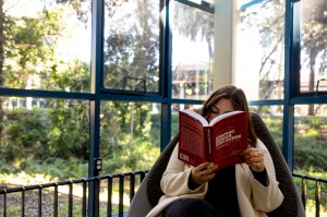 A student reading a book entitled Graphic Design Discourse in a sunny corner.