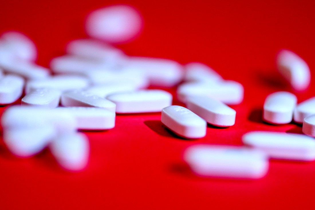 White Tylenol pills spread out on a red surface.
