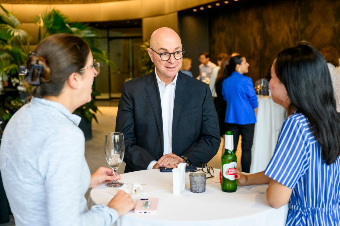 Joseph E. Aoun chats with two female faculty members at a high-top table.