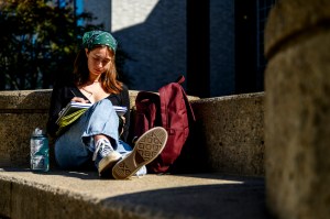Meredith Jenkins, a Northeastern student studying economics and health services, works on a project while sitting outside Richardson Plaza with her notebook, backpack and water bottle.