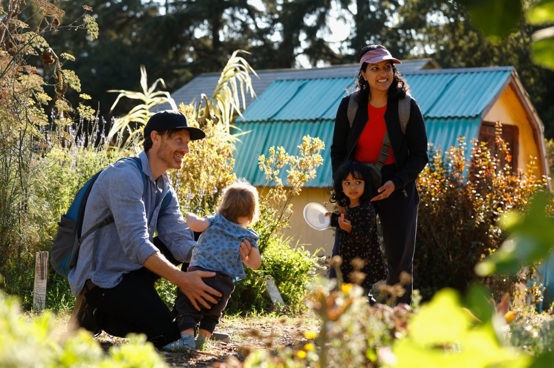 Two people, each with a young child, outside at the Oakland Farm Festival.