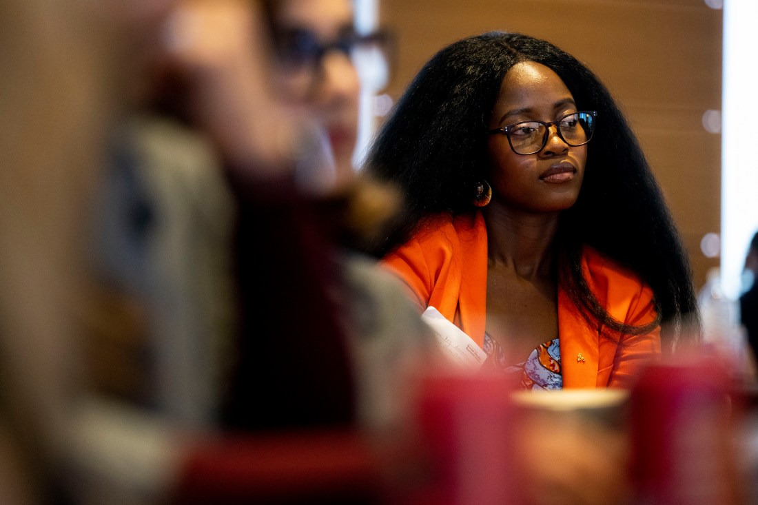 A woman wearing glasses and an orange blazer listens intently at the Social Media Summit. 
