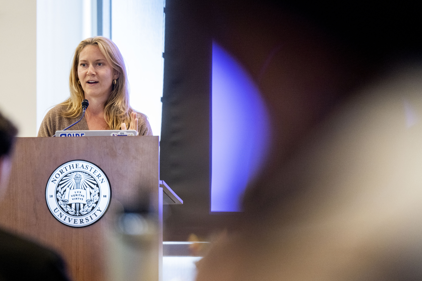 Emily Schario standing at a wooden podium with the Northeastern seal on it while presenting at the Social Media Summit. 