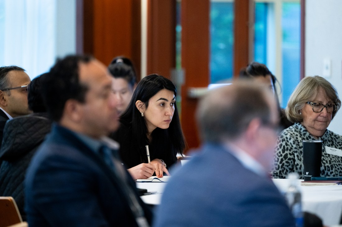 Professionals seated at tables with laptops and notebooks attend a workshop training session.