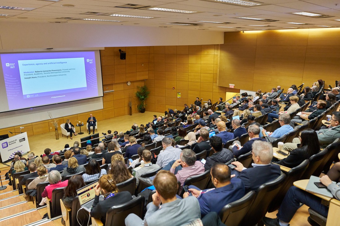 A view of the packed lecture hall as Joseph Aoun and Roberta Iannacito-Provenzano engage in conversation under a large projector.