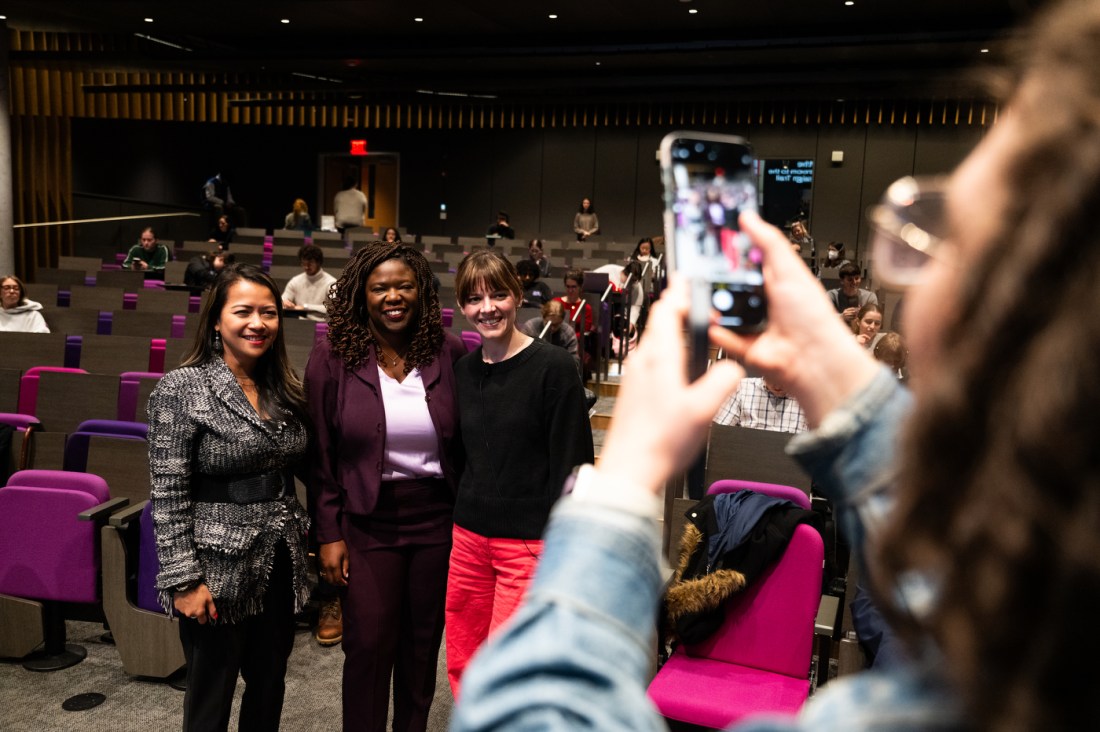 A group of three students take a photo together as another holds up an iPhone at the Civic Experience: From the Classroom to the Campaign Trail lecture series.