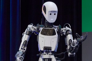 A humanoid robot with white body segments and a neutral expression gestures with a hand.