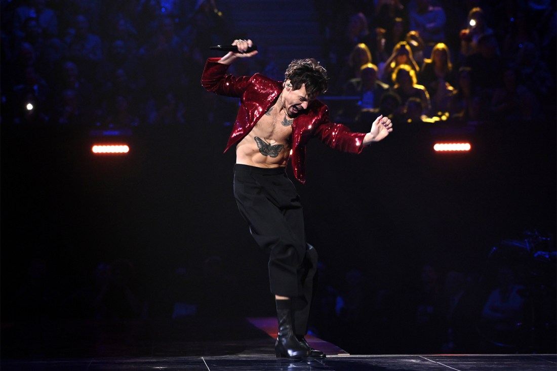 Musician Harry Styles dances on stage with his chest and stomach exposed.