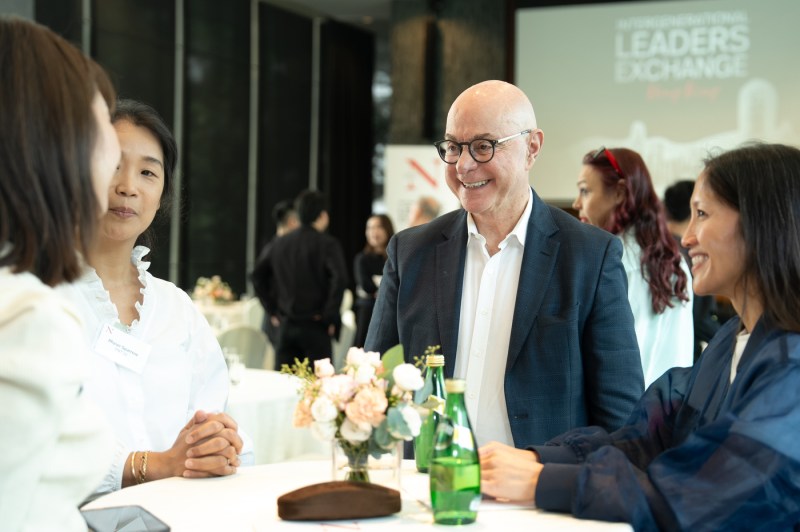 President Aoun smiling and conversing with three people at a table at a networking reception.