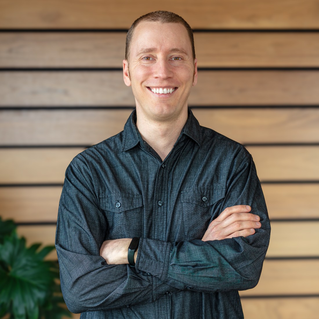 Julien Jalbert smiling and posing for a portrait with his arms folded. 