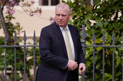 Prince Andrew, the Duke of York, looking over his shoulder while wearing a suit.